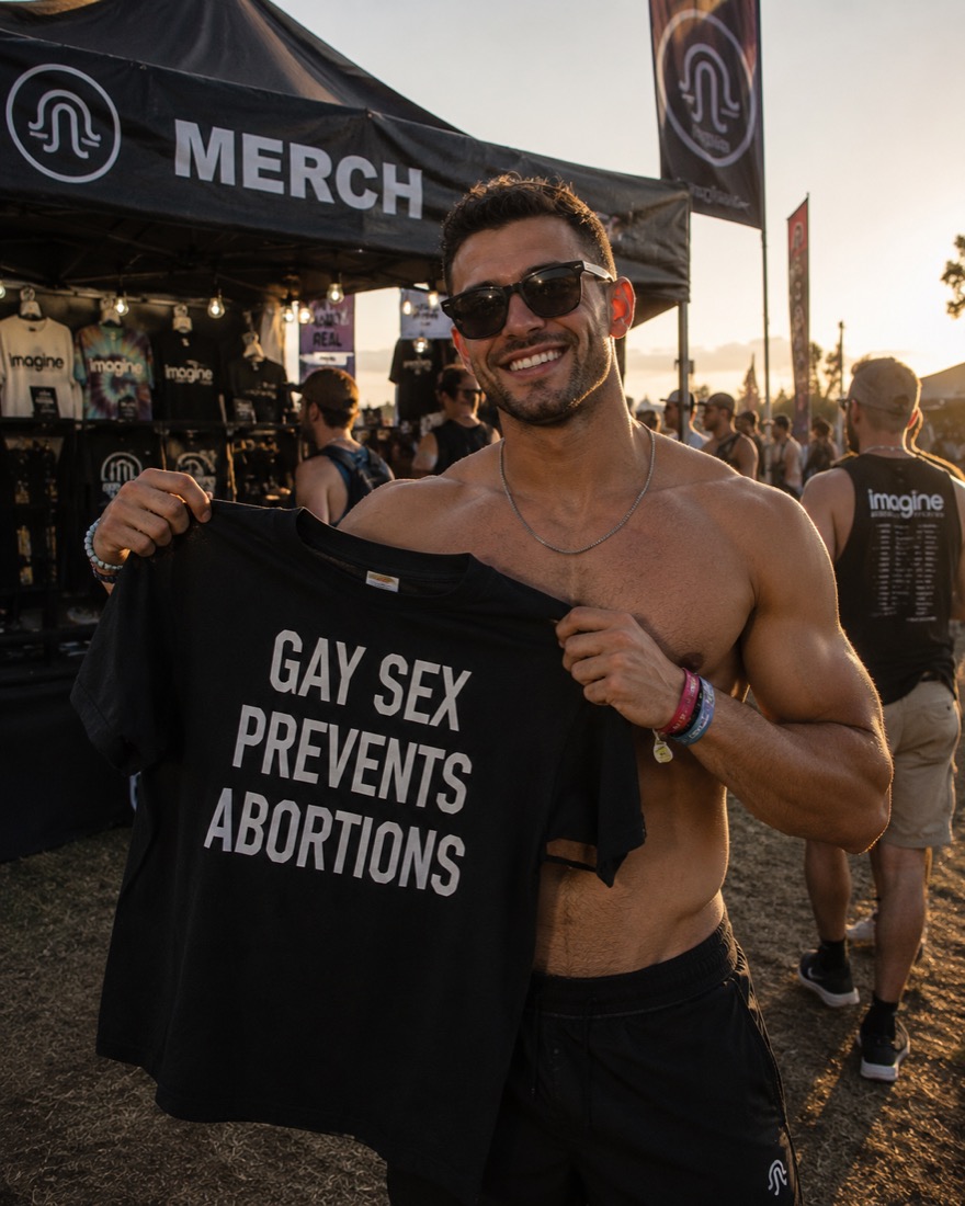 A person holding up the GAY SEX PREVENTS ABORTIONS t-shirt at an outdoor merch booth
